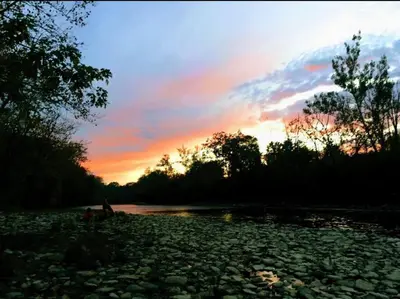 a group of people sitting on the rocks near a river at Updated 3bd Cottage on Bike Trail w/ River access! in Loveland