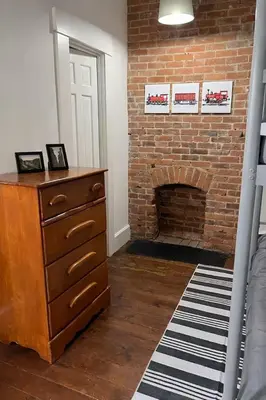 a bedroom with a brick fireplace and a dresser and a bed at 