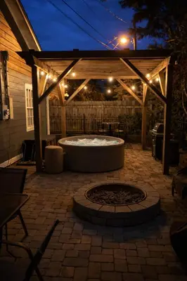 a patio with a hot tub under a pergola with lights at 