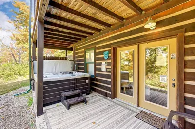 a porch with a tub on the side of a house at Large Log Cabin Chalet w/ Hot Tub - Horses & Lake! in Loveland