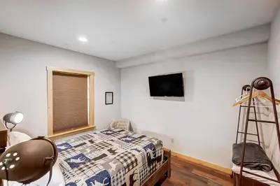 a bedroom with a bed and a tv on the wall at Large Log Cabin Chalet w/ Hot Tub - Horses & Lake! in Loveland