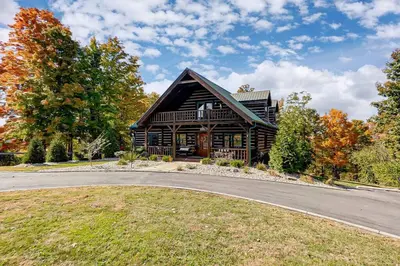 a large wooden house with a road in front of it at Large Log Cabin Chalet w/ Hot Tub - Horses & Lake! in Loveland