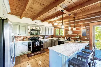 a kitchen with wooden ceilings and a large counter top at Large Log Cabin Chalet w/ Hot Tub - Horses & Lake! in Loveland