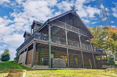a large wooden house on top of a hill at Large Log Cabin Chalet w/ Hot Tub - Horses & Lake! in Loveland