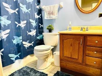 a bathroom with a toilet and a blue shower curtain at Ocean Palace -12 Guests- close to I-75-Amazing Location!! in Maud