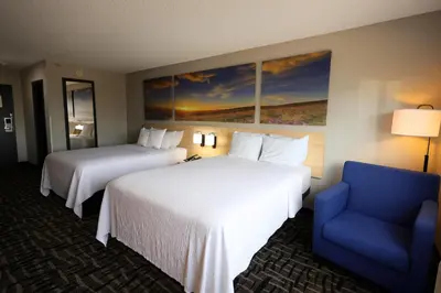 a hotel room with two beds and a blue chair at Days Inn by Wyndham Jackson in Jackson