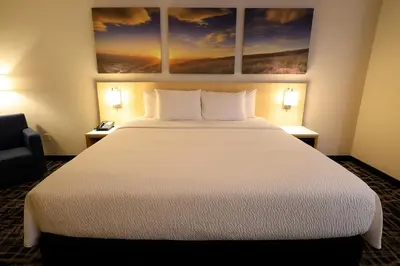a hotel room with a large white bed and a chair at Days Inn by Wyndham Jackson in Jackson