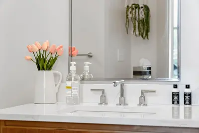 a bathroom sink with a vase of flowers and a mirror at Flatiron Bldg - Views - Amazing Cafe - Near to ALL in Cincinnati