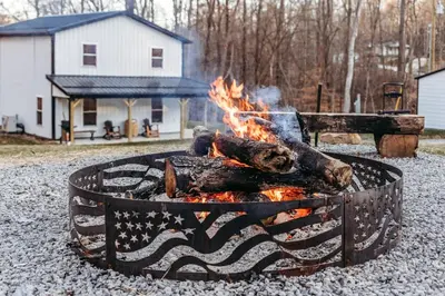 a fire pit with logs in it in front of a house at Modern Salineville Cabin on 13 Acres with Fire Pit! in Salineville