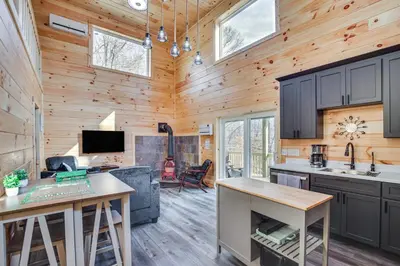 a kitchen and living room in a log cabin at Modern Salineville Cabin on 13 Acres with Fire Pit! in Salineville