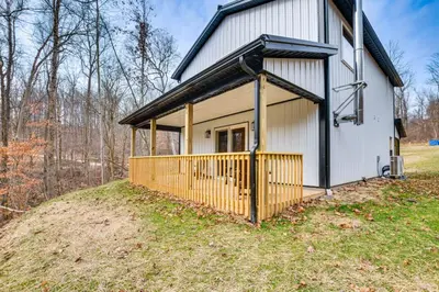 a white house with a gate on a hill at Modern Salineville Cabin on 13 Acres with Fire Pit! in Salineville