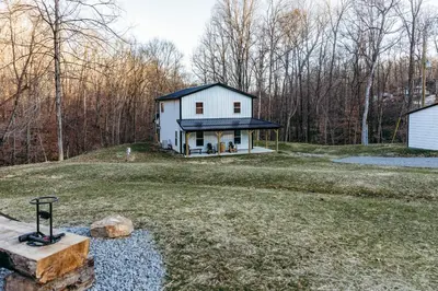 a white house with a blue roof on a yard at Modern Salineville Cabin on 13 Acres with Fire Pit! in Salineville