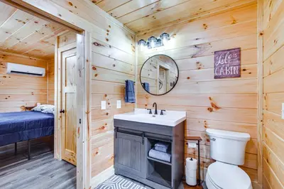 a bathroom with a sink and a toilet in a log cabin at Modern Salineville Cabin on 13 Acres with Fire Pit! in Salineville