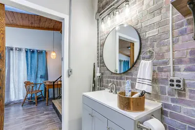a bathroom with a brick wall and a mirror at Cozy Tiffin House with Private Pool 1 Mi to Town! in Tiffin