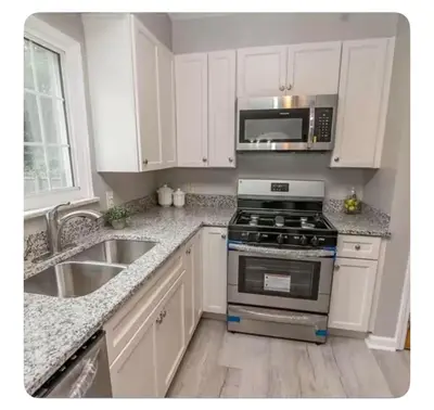 a kitchen with white cabinets and a stove and a sink at Private suite near Cleveland Clinic in Shaker Heights