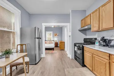 a kitchen with a stainless steel refrigerator and a table at Historic Cozy Haven in Little Italy in Cleveland