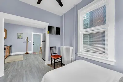 a bedroom with a bed and a chair and a window at Historic Cozy Haven in Little Italy in Cleveland