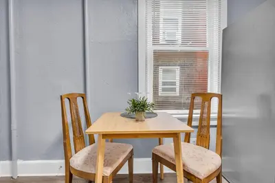 a wooden table with two chairs and a vase with flowers at Historic Cozy Haven in Little Italy in Cleveland