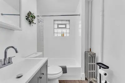 a white bathroom with a toilet and a sink at Historic Cozy Haven in Little Italy in Cleveland