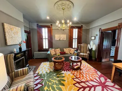 a living room with a couch and a chandelier at Skyline Retreat Spacious Elegance Queen Suite 1 City Views in Cincinnati