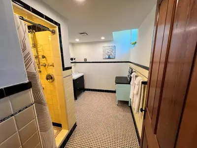 a bathroom with a sink and a shower with yellow tiles at Skyline Retreat Spacious Elegance Queen Suite 1 City Views in Cincinnati