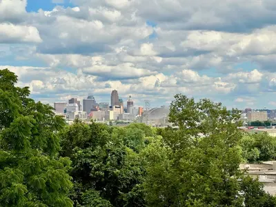 a view of a city from behind some trees at Skyline Retreat Spacious Elegance Queen Suite 3 City Views in Cincinnati