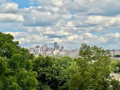 a view of a city from behind some trees at Skyline Retreat Spacious Elegance Queen Suite 4 City Views in Cincinnati