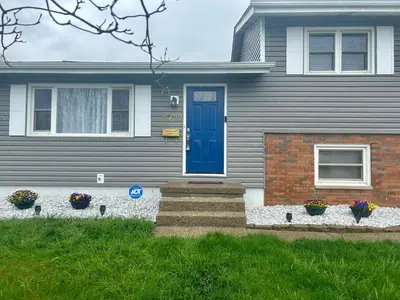 a house with a blue door and flowers in a yard at Cozy 3 Bedroom Home in Reynoldsburg