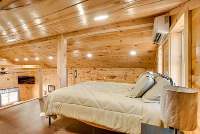 a bedroom with a bed in a room with wooden walls at Friends and Family Rental Cabin with Hot Tub! in Somerset
