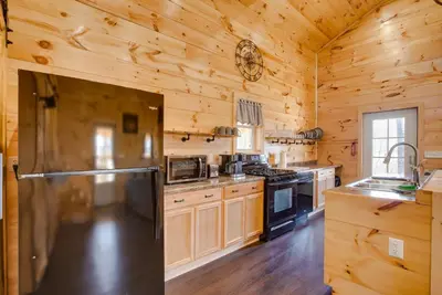 a large kitchen with wooden walls and a refrigerator at Friends and Family Rental Cabin with Hot Tub! in Somerset