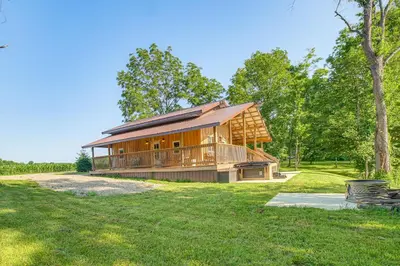 a large wooden house in the middle of a field at Friends and Family Rental Cabin with Hot Tub! in Somerset