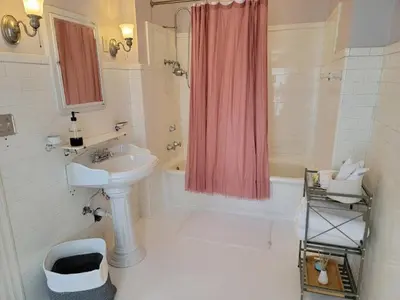 a white bathroom with a sink and a shower curtain at The Kings Throne Inn and Guest House in Toledo