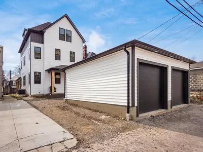 a building with a four door garage next to a house at Modern Luxury 4BR 3 5BA Oasis in Historic Old Town East PD in Columbus