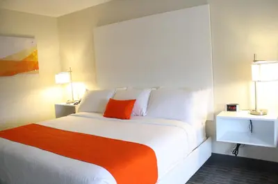 a bedroom with a large white bed with an orange pillow at Schoenbrunn Inn in New Philadelphia