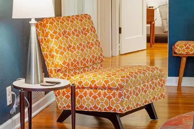 an orange chair sitting next to a table with a lamp at Refreshing Mid Mod Retreat BG in Bowling Green