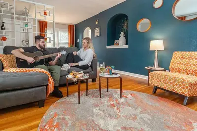 a man and woman sitting in a living room playing guitar at Refreshing Mid Mod Retreat BG in Bowling Green