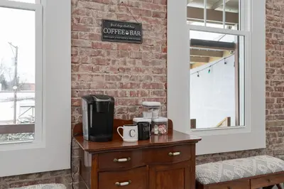 a coffee maker on a table next to a brick wall at Private Boutique Getaway - Fireplace & Soaking Tub - Downtown Loft - by Cross-Key Vacation Rentals in Millersburg