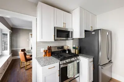 a kitchen with white cabinets and a black refrigerator at Modern 3BR Near Cleveland Clinic in Cleveland Heights