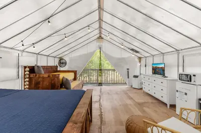 a bedroom in a greenhouse with a bed and a tv at River Front Hallowed Horse Glamp Tent 2 in Stanton