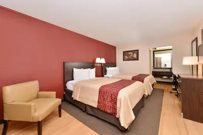 a hotel room with two beds and a chair at Red Roof Inn Marietta in Marietta