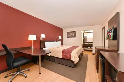 a hotel room with a bed and a desk and a television at Red Roof Inn Marietta in Marietta