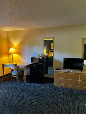 a hotel room with a desk and a table and a room at Ameristay Inn & Suites in Waverly