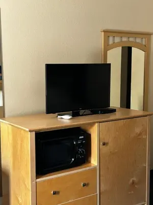 a tv on top of a wooden stand with a microwave at Ameristay Inn & Suites in Waverly