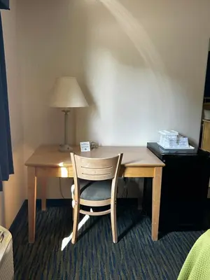 a wooden desk with a chair and a lamp at Ameristay Inn & Suites in Waverly
