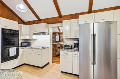 a kitchen with white cabinets and a stainless steel refrigerator at Log Cabin - Natures Oasis - Fire Pit & Gazebo in Cleveland