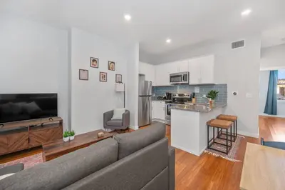a living room with a gray couch and a kitchen at Prime OTR off Vine St, Lux Full Bed, Fast WiFi, Fully Equipped, 50in TV, Sleeps 4ppl in Cincinnati