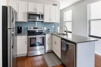 a kitchen with white cabinets and stainless steel appliances at OTR, QUEEN Bed, 50in TV, Workspace, Near Lightrail in Cincinnati