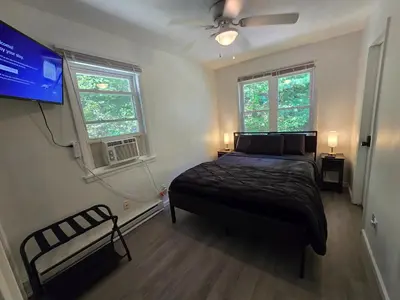 a bedroom with a bed and a tv and two windows at Turkey Trot, Cabin Getaway on Lake w/ Hot Tub in Streetsboro