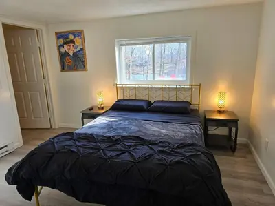 a bedroom with a bed with two night stands and a window at Eagles Nest At Heron Hill Retreat Hot Tub on Lake! in Streetsboro