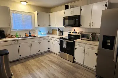 a kitchen with white cabinets and black appliances at Eagles Nest At Heron Hill Retreat Hot Tub on Lake! in Streetsboro